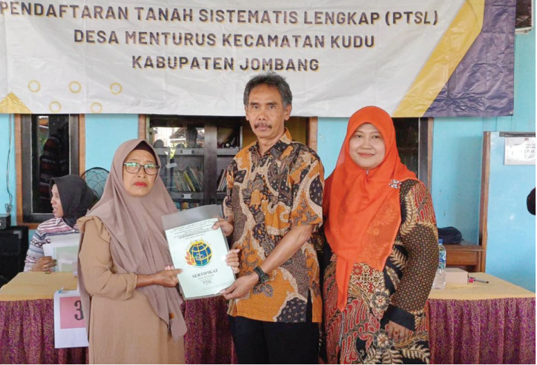 Kepala Desa Menturus Nyamiati (kerudung orange) menyerahkan sertifikat PTSL kepada warganya.
