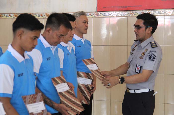 KHIDMAT: Plh Kalapas Jombang Dedy Pranata menyerahkan remisi khusus kepada belasan warga binaan, Senin (25/12).