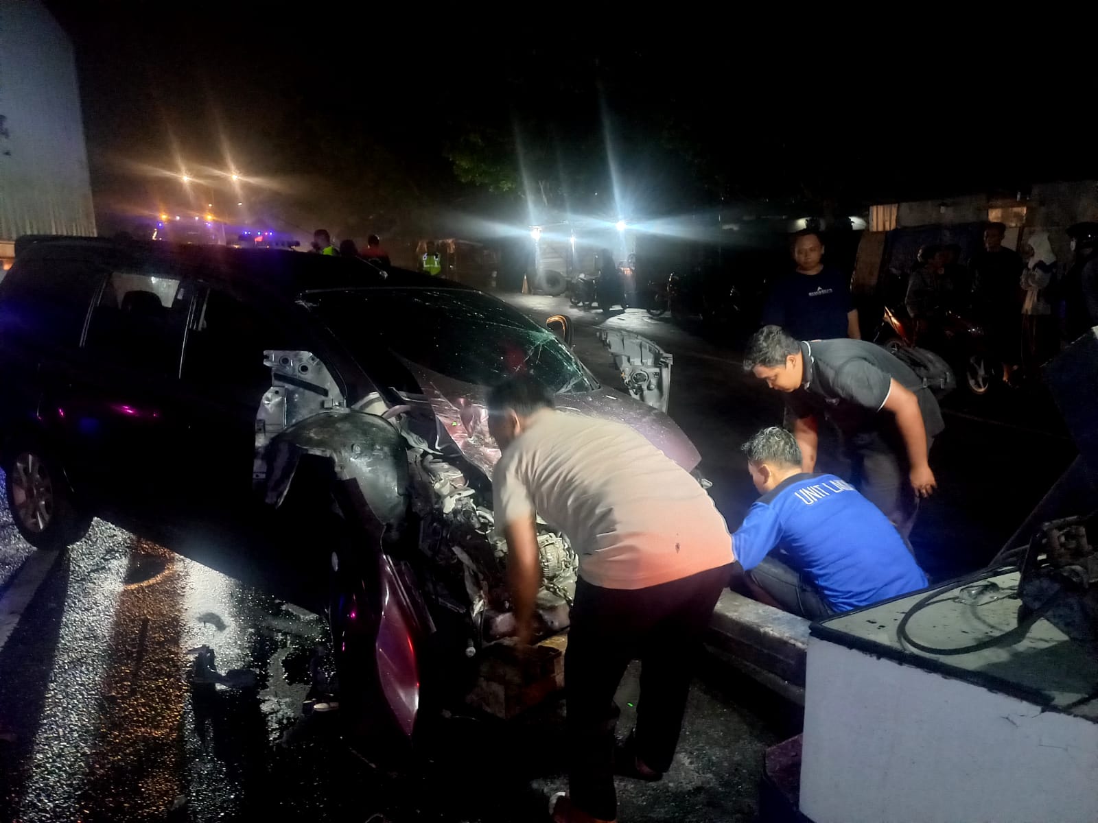 Petugas mengevakuasi mobil Grand Livina yang ringsek usai dihantam elf di Jalur arteri Nasional Tejo, Mojoagung, Jombang Selasa (26/12) malam.