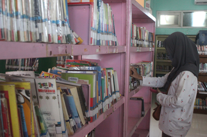 Pengunjung perpustakaan Mastrip sedang memilih buku untuk dibaca di rak yang disediakan.