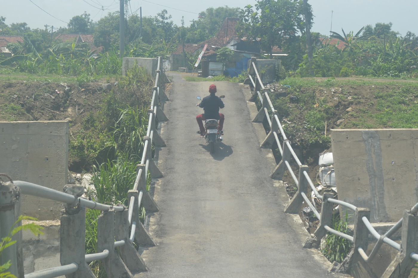 Warga melintasi jembatan melengkung atas Kali Konto Desa Barongsawahan, Kecamatan Bandarkedungmulyo, Jombang. Karena tak masuk prioritas perbaikan, jembatan melengkung ini rencananya bakal dibongkar.