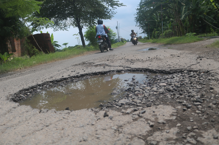 Kondisi jalan kabupaten di Desa Kedungmlati, Kesamben, Jombang yang berlubang dan mengancam pengendara.