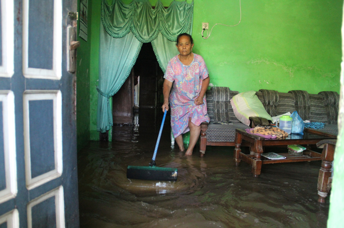 MASUK RUMAH: Warga Dusun Nglajur, Desa Tugusumberejo, Kecamatan Peterongan membersihkan air yang masuk ke dalam rumah, Senin (26/2).