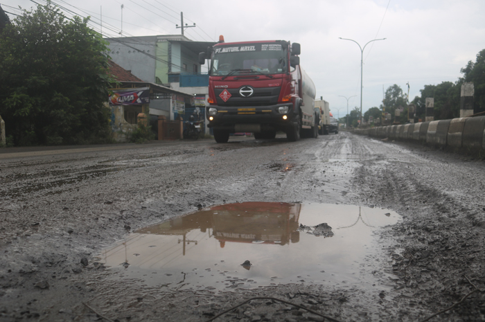 Kondisi jalur contraflow di pinggir proyek pembongkaran cor beton jalan nasional Jombang yang bergelombang dan licin setelah hujan.