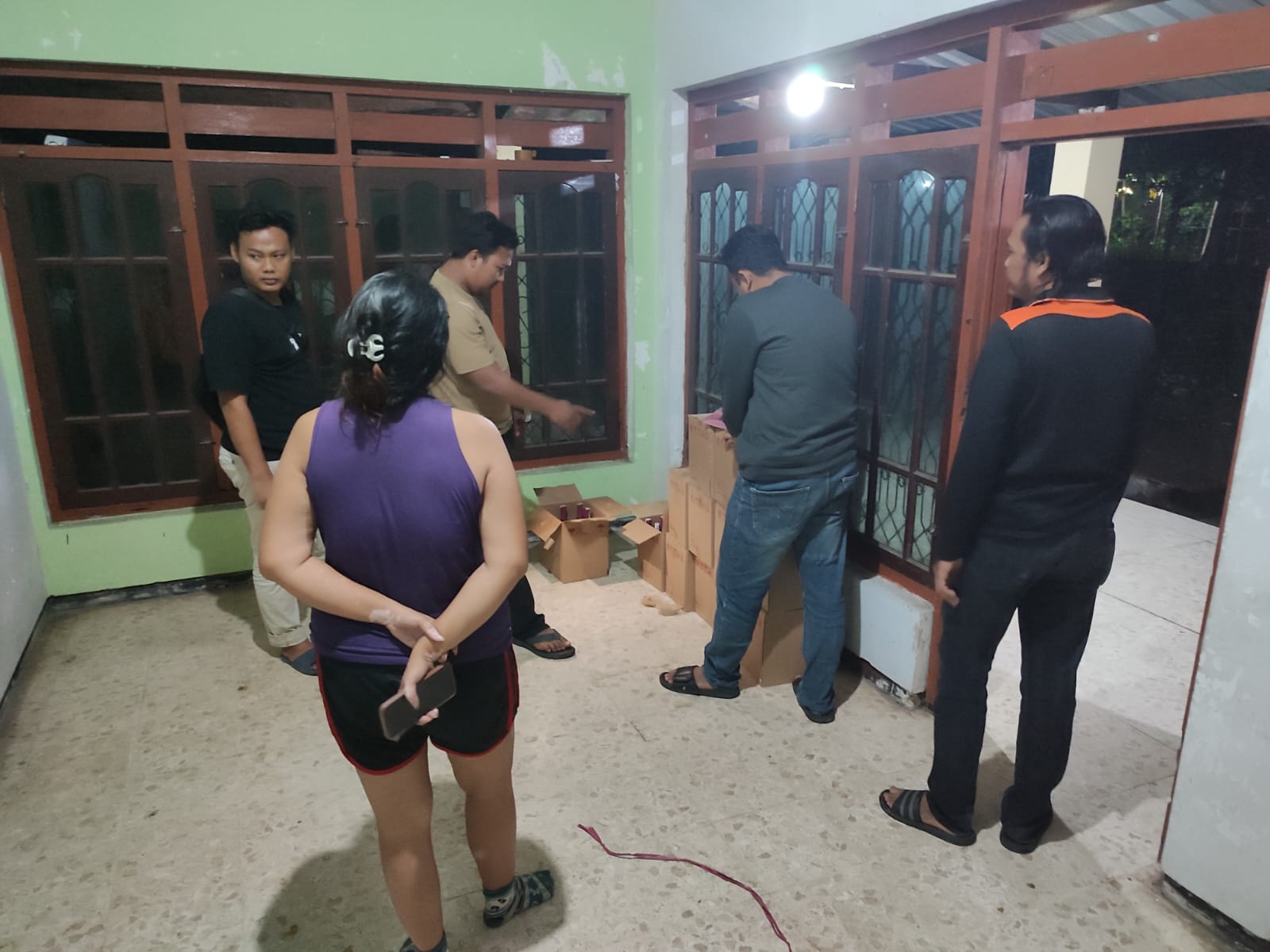 Polisi saat melakukan penggerebekan di rumah SPG rokok dan mengamankan ratusan botol miras