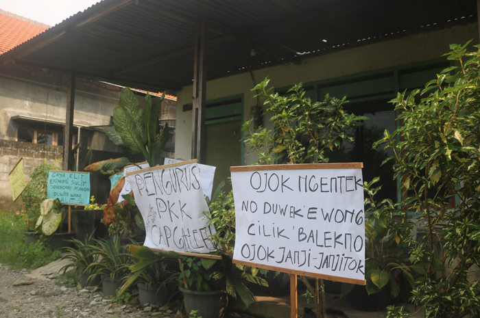 Poster protes yang dipasang warga di depan rumah L dan E, perangkat desa Mancar, Kecamatan Peterongan yang diduga membawa lari uang tabungan PKK