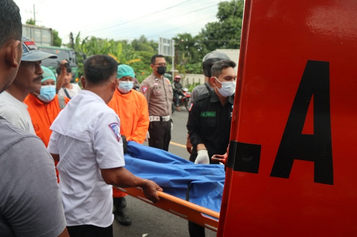 DIEVAKUASI: Petugas mengevakuasi korban yang tewas usai gagal nyalip dan menabrak pohon di jalan nasional Jombang.