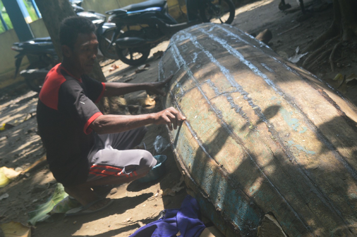 Samiran salah seorang pencari ikan Sungai Brantas tengah memperbaiki perahu yang rusak di Desa Sudimoro, Kecamatan Megaluh Jombang