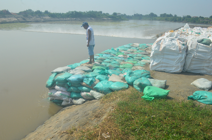 Salah seorang penjaga Dam Karet Jatimlerek di sisi Desa Sudimoro, Kecamatan Megaluh berada di antara sandbag yang baru saja dipasang dekat pintu enam yang jebol.