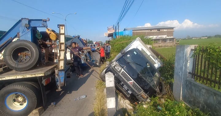 Proses evakuasi mobil box yang terguling ke saluran pinggir jalan nasional dan menimpa sebuah motor