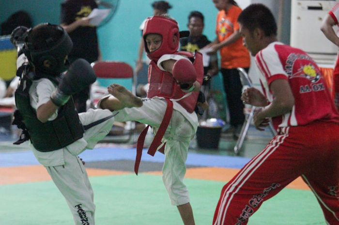 Nizar (merah) petarung dari Jombang saat bertanding melawan atlet dari Surabaya (hitam) di Gelanggang Remaja Surabaya, Minggu (2/6).