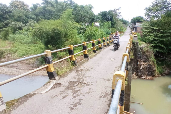 Warga melintas di jembatan Desa Banjaragung, Kecamatan Bareng terdampak banjir 2021 akan diperbaiki pemerintah pusat (29/3).