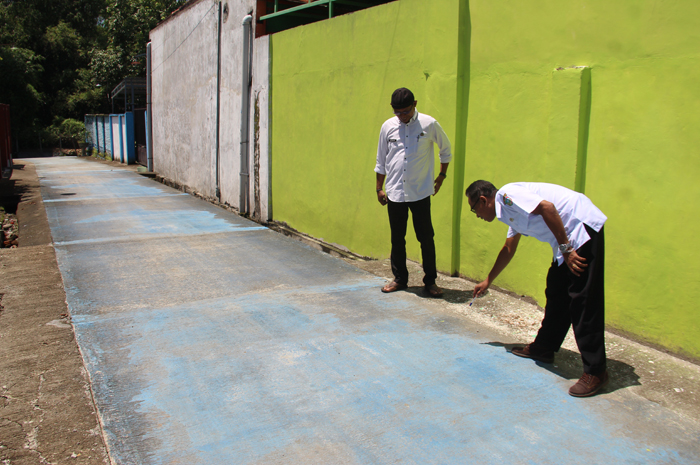 : Kepala Desa Mojowarno Tatag Yudianto didampingi Hendriyanto Kaur Perencanaan, menunjukkan jalan rabat beton penghubung antar RT di desanya yang telah tuntas dibangun.