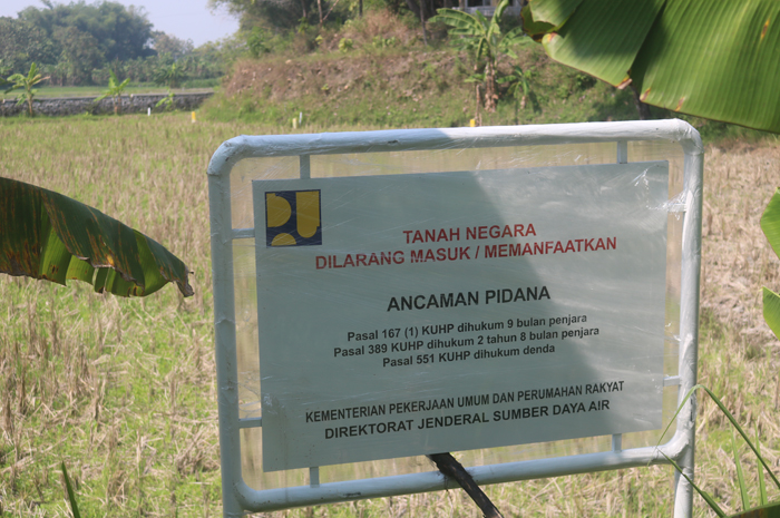 Papan larangan dari Kementrian PUPR yang telah dipasang di lokasi lahan yang akan digunakan sebagai embung Purisemanding