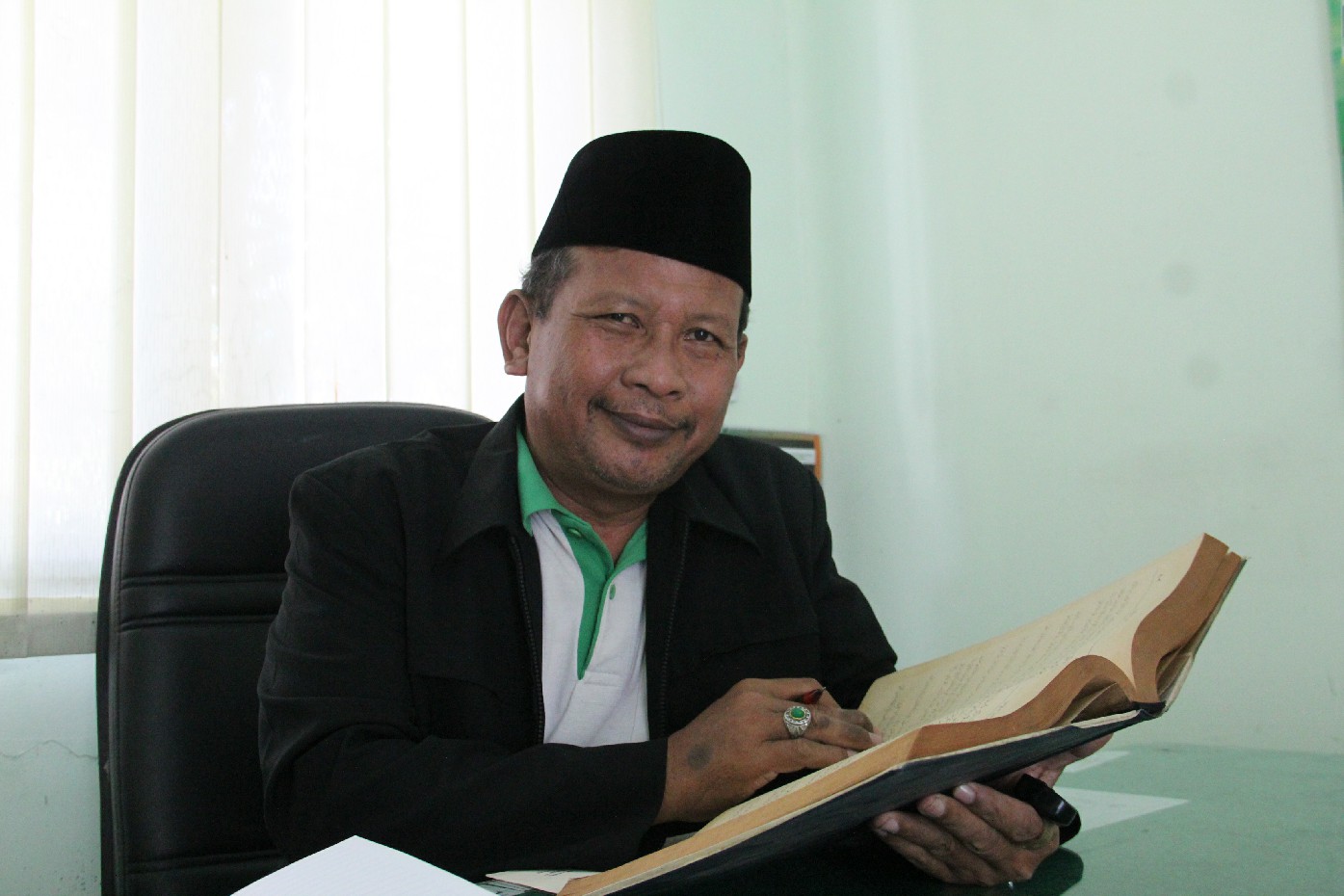 Kepala Seksi Pendidikan Diniyah dan Pondok Pesantren (PD-Pontren) Kemenag Jombang, Drs H Muhammad Agussalim MH, membaca kitab di ruangannya, Jumat (20/9).