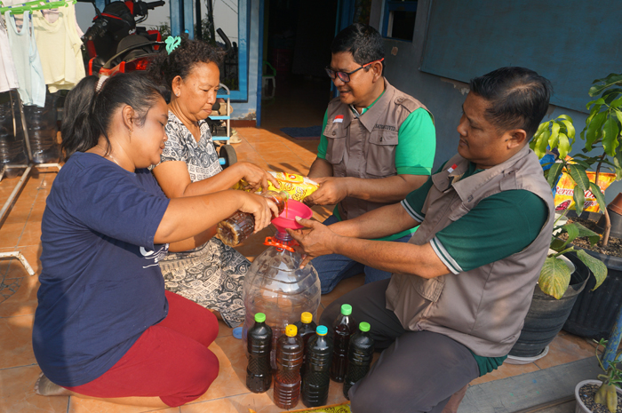 Petugas Kelurahan Jelakombo mengumpulkan minyak sisa hasil penggorengan rumah tangga dari para warga dalam program Sedekah Jelantah.
