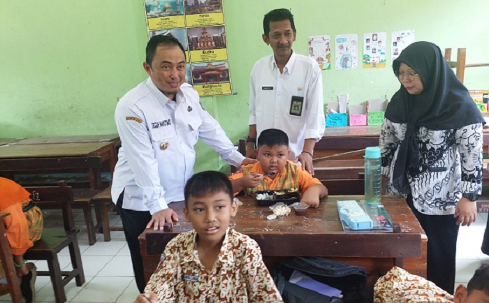 Kepala Desa Kepatihan Erwin Pribadi mendampingi Pj Bupati Jombang Teguh Narutomo saat meninjau simulasi program makan siang gratis di SDN Kepatihan