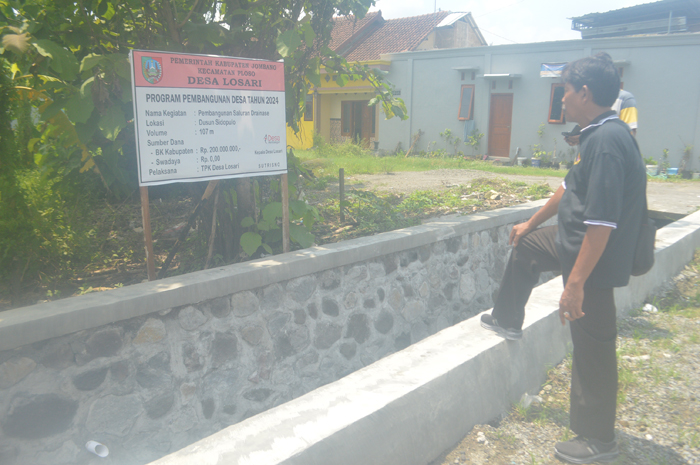 Kades Losari Sutrisno (pakai topi) menunjukkan saluran drainase baru saja selesai dibangun.