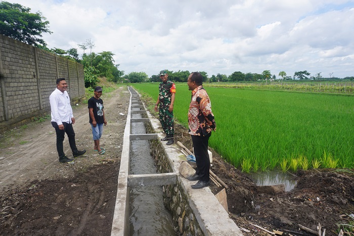 ATASI BANJIR: Kepala Desa Kepala Desa Gempollegundi Sagiyan Taruna Alip (baju batik) didampingi perangkat desa, ketua TPK dan perwakilan Tiga Pilar saat menunjukkan lokasi pembangunan saluran drainase