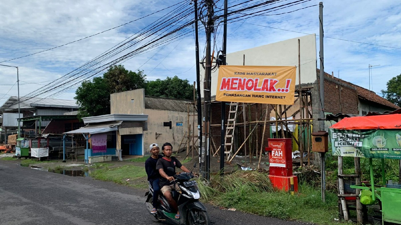 Sejumlah warga Desa Tugusumberjo, Kecamatan Peterongan memasang spanduk penolakan pemasangan tiang internet fiber optik (FO) di Jalan Kolonel Haji Ismail, Jumat (3/1).