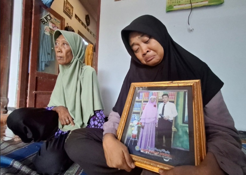 Widyawati, 43, kakak Septian Adi Ferdiansyah menunjukkan foto semasa hidup adiknya ditemani Supiyah, sang ibu.
