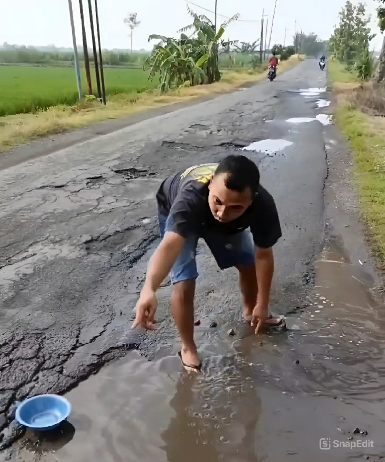 Warga saat menangkap ikan dalam sebuah kubangan jalan rusak di Desa Watudakon Kecamatan Kesamben Jombang sebagai bentuk sindiran karena perbaikan jalan berlangsung lamban