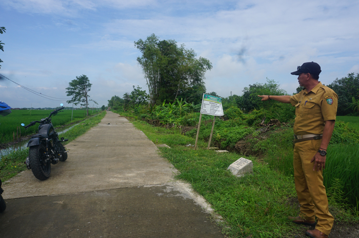 Kasi Kesra Kedungbetik Harianto saat menunjukkan lokasi pembangunan JUT di Dusun/Desa Kedungbetik.