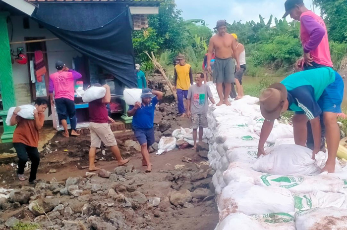 warga membuat tanggul darurat untuk menutup parapet Sungai Catakbanteng yang jebol