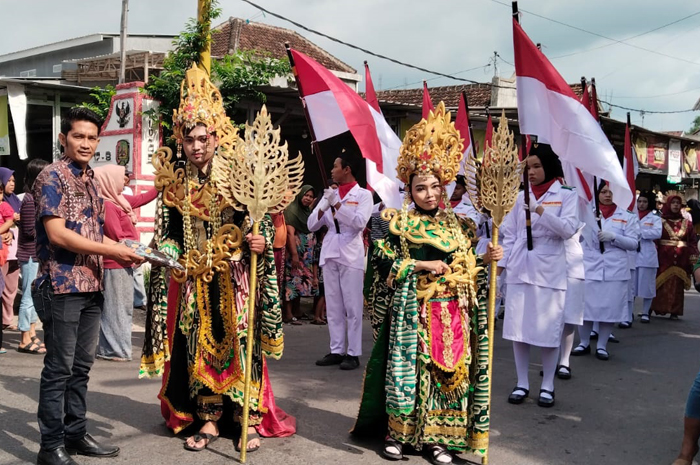 Maskot pawai budaya SMPN 2 Tembelang memberikan hasil karya batik serta produk ikon sekolah berupa sirup markisa buatan siswa kepada Kepala Desa Pulorejo, Deny Sparingga.