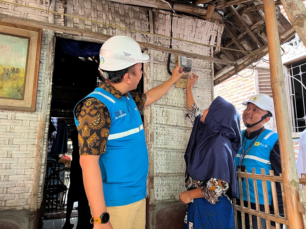 Manajer PLN UP3 Mojokerto Muhammad Syafdinuur bersama penerima bantuan secara simbolis menyalakan meteran listrik bantuan listrik gratis.