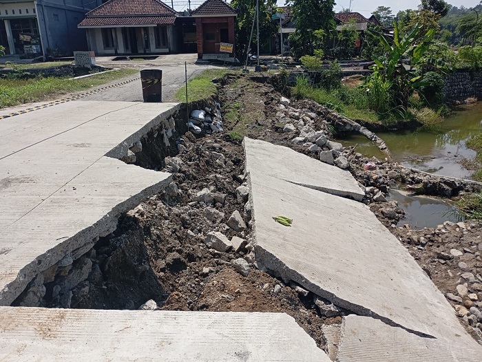 RUSAK: Kondisi tembok penahan jalan beserta cor jalan di Desa Asemgede, Kecamatan Ngurikan yang ambrol, Minggu (18/5).
