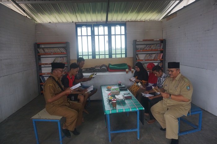 SEMANGAT LITERASI: Kepala Desa Keras Sukardi dan Camat Diwek Agus Sholihudin membaur bersama warga setempat saat membaca buku di perpustakaan Desa Keras.