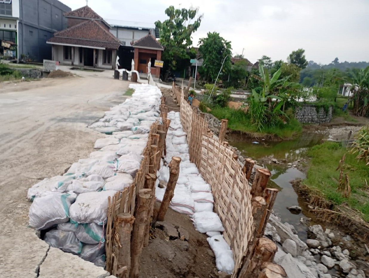 MULAI DITANGANI: Penanganan darurat dilakukan pada banguan tembok penahan jalan di Desa Asemgede Kecamatan Ngusikan yang ambrol.