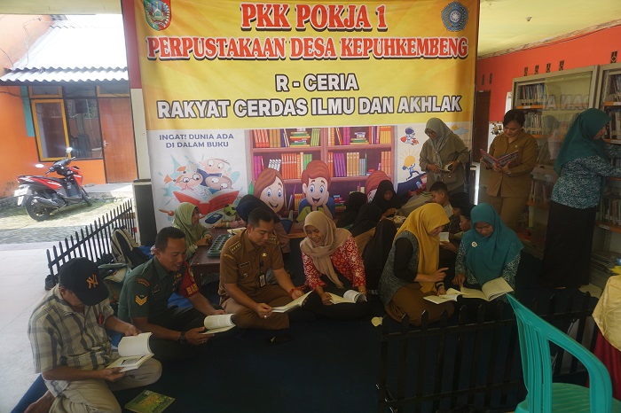JENDELA ILMU: Camat Peterongan Mohammad Eryk Arif didampingi Sekretaris Desa Kepuhkembeng Anis Prasetyo Ari dan jajaran pengelola perpusdes saat membaca buku bersama anak-anak serta warga setempat di