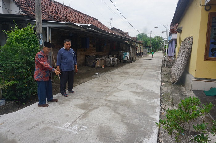 TINGKATKAN AKSES JALAN LINGKUNGAN: Kepala Desa Pagwerwojo Imam Wahyudi (kiri) mendampingi Camat Perak Supriyono saat meninjau lokasi pembangunan jalan rabat beton di Dusun Ngemplak.