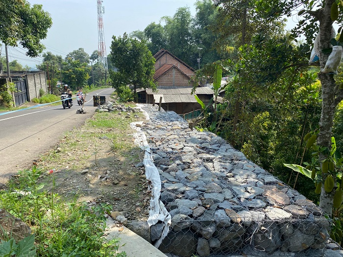 DITANGANI DARURAT: Kondisi tembok penahan jalan (TPJ) yang longsor di Desa Pulosari Kecamatan Bareng ditangani darurat, Minggu (29/6).
