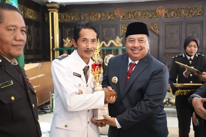 KOMITMEN KEAMANAN: Kades Mentoro Mahfudz Efendi saat menerima piala penghargaan juara Harapan 1 Kapolres Award Desa Aman 2025 dari Bupati Jombang Warsubi di pendopo Kabupaten Jombang, Selasa (1/7) pag