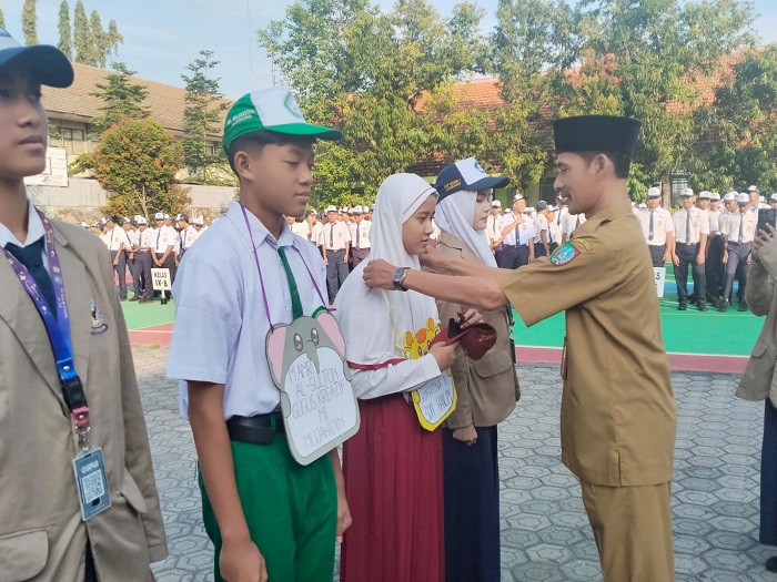 PENYEMATAN: Kepala SMPN 1 Jombang, Rudy Priyo Utomo MPd, menyematkan tanda peserta MPLS
