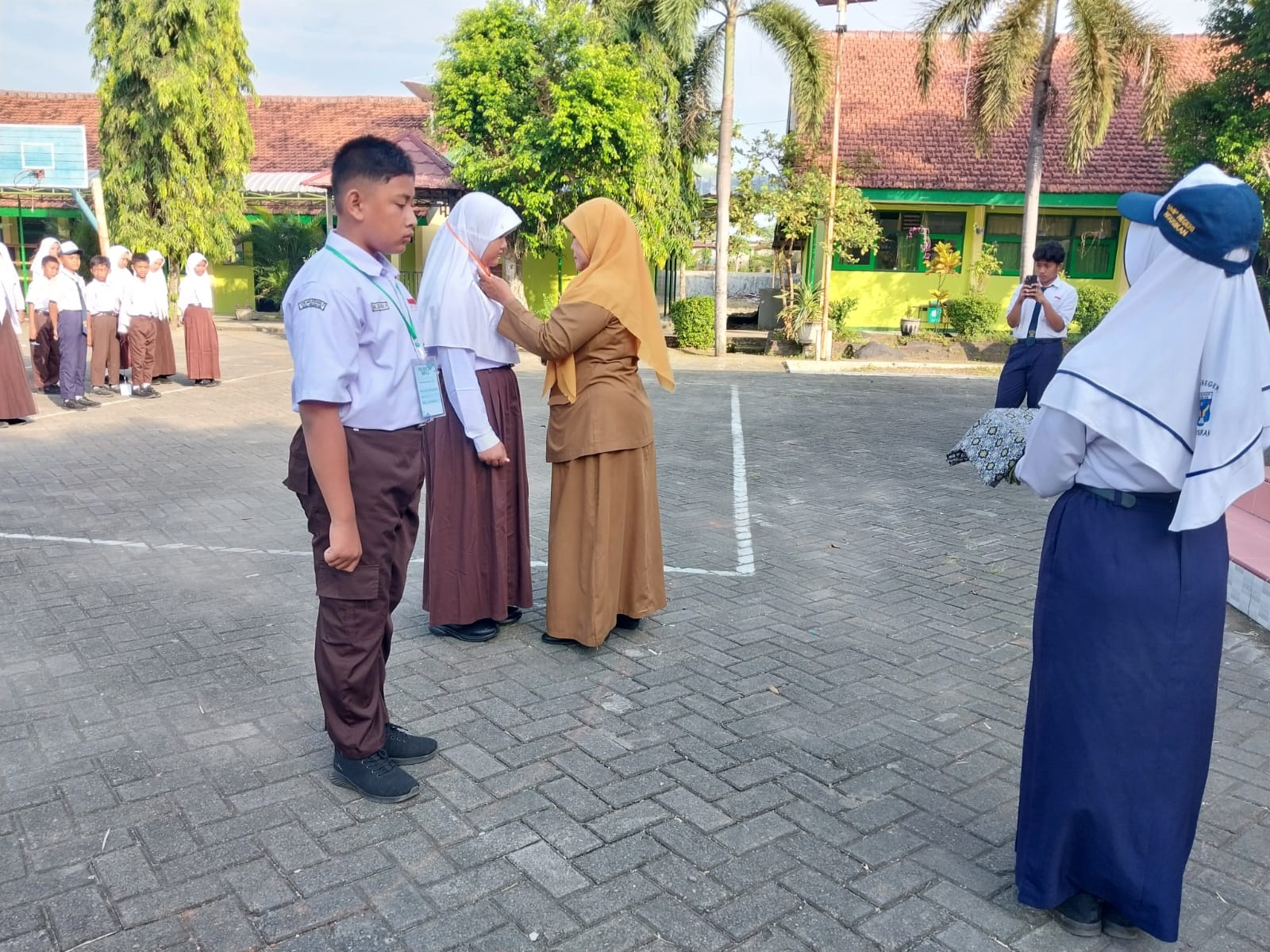 SAMBUT SISWA BARU: Kepala SMPN Ngusikan, Sanuriyawati SPd, memasang identitas kepada perwakilan peserta MPLS.