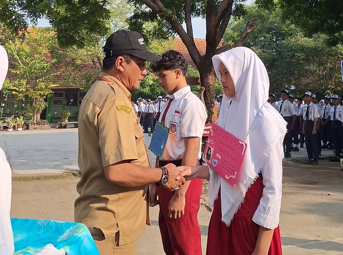 TELADAN: Kepala SMPN 3 Mojoagung, Zainul Arifin, menyematkan tanda peserta kepada siswa kelas 7, Senin (14/7).