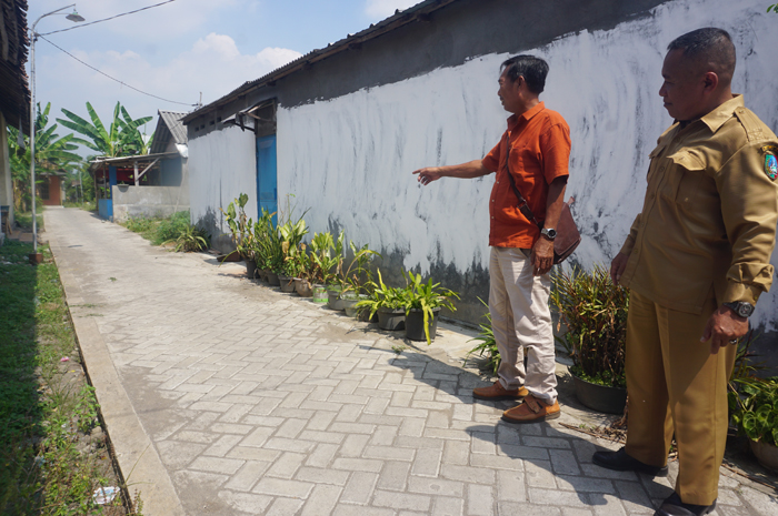 TUNJANG MOBILITAS WARGA: Kepala Desa Janti H Musta&rsquo;in didampingi salah satu perangkat desa saat meninjau lokasi pembangunan jalan paving di Dusun/Desa Janti.