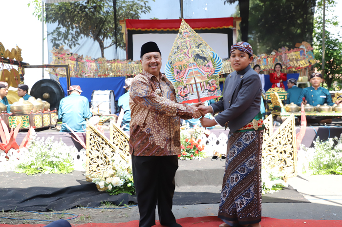 Bupati Warsubi menyerahkan wayang kepada dalang cilik, Amoro Lingga Abinaya (siswa kelas 7 SMPN Plandaan), membuka gelaran Wayang Masuk Sekolah di Perguruan Muhammadiyah Mentoro, Sumobito, Jombang