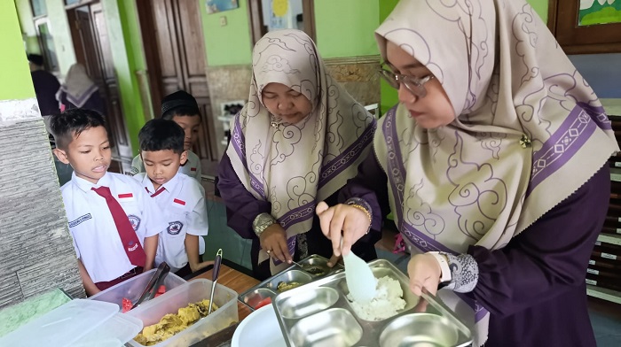 ANTUSIAS: Sejumlah guru SD Islam Roushon Fikr saat mengambilkan menu makan di sekolah, kemarin (3/10).