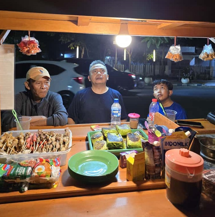 TELADAN: Wakil Ketua DPRD Jombang, HM Syarif Hidayatullah ST MMT (Gus Sentot), menikmati angkringan milik komedian Dika Mbeluk di depan Polres Jombang, Minggu (12/10).  &nbsp;