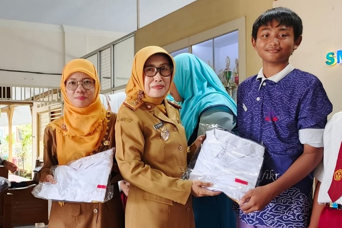 Kepala Dinas P dan K Jombang, Wor Windari menyerahkan seragam gratis ke siswa.