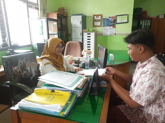 TOTALITAS: Pegawai tidak tetap SMAN 2 Jombang, Dianita Mey Ratnasari, yang diangkat menjadi PPPK Paruh Waktu saat memberikan pelayanan di meja kerjanya, Rabu (12/11).  &nbsp;