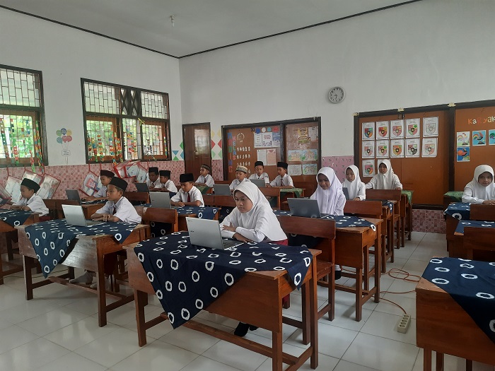 TELATEN: Aris Zainul Imam, guru PAI SDN Kepuhkajang 2 Perak saat membantu siswa mengoperasikan chromebook.  &nbsp;