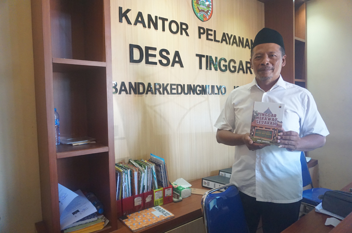 LANDASAN SEJARAH DESA: Kepala Desa Tinggar Mohamad Madram menunjukkan buku Tinggar Merawat Sejarah.