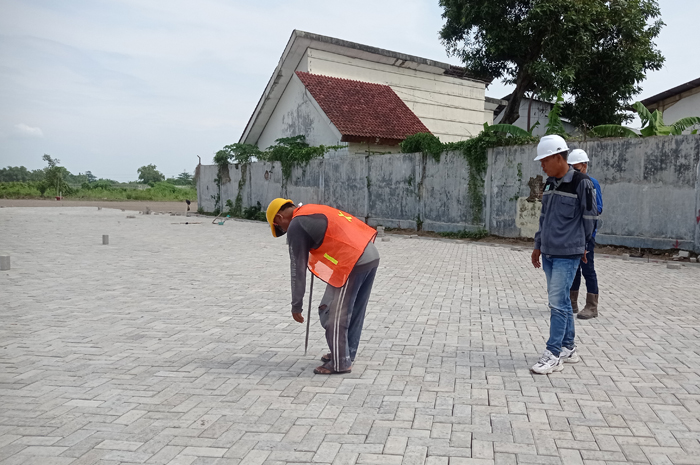 DIKEBUT: Pekerja memasang paving di lokasi Terminal Barang Desa Glagahan, Kecamatan Perak.