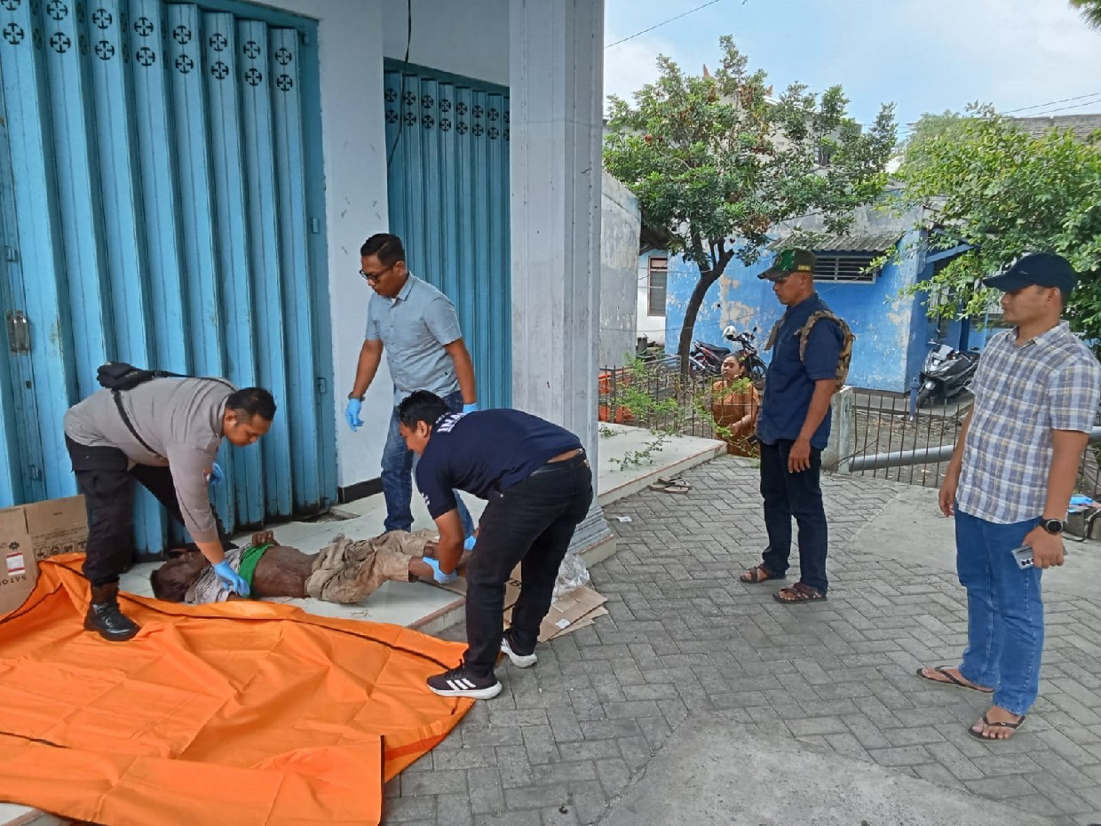 Petugas saat mengevakuasi jasad pria di depan ruko Mojoagung Jombang